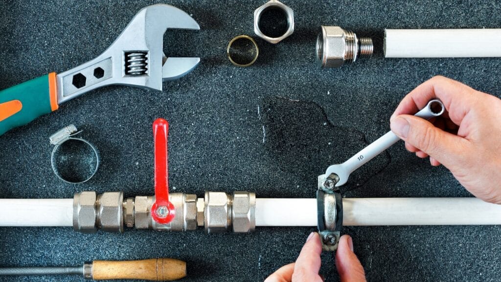 Plumber repairing a pipe valve with an adjustable wrench in Peachtree City