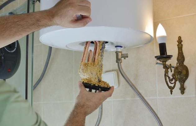 Technician removing mineral buildup from a water heater in Peachtree City