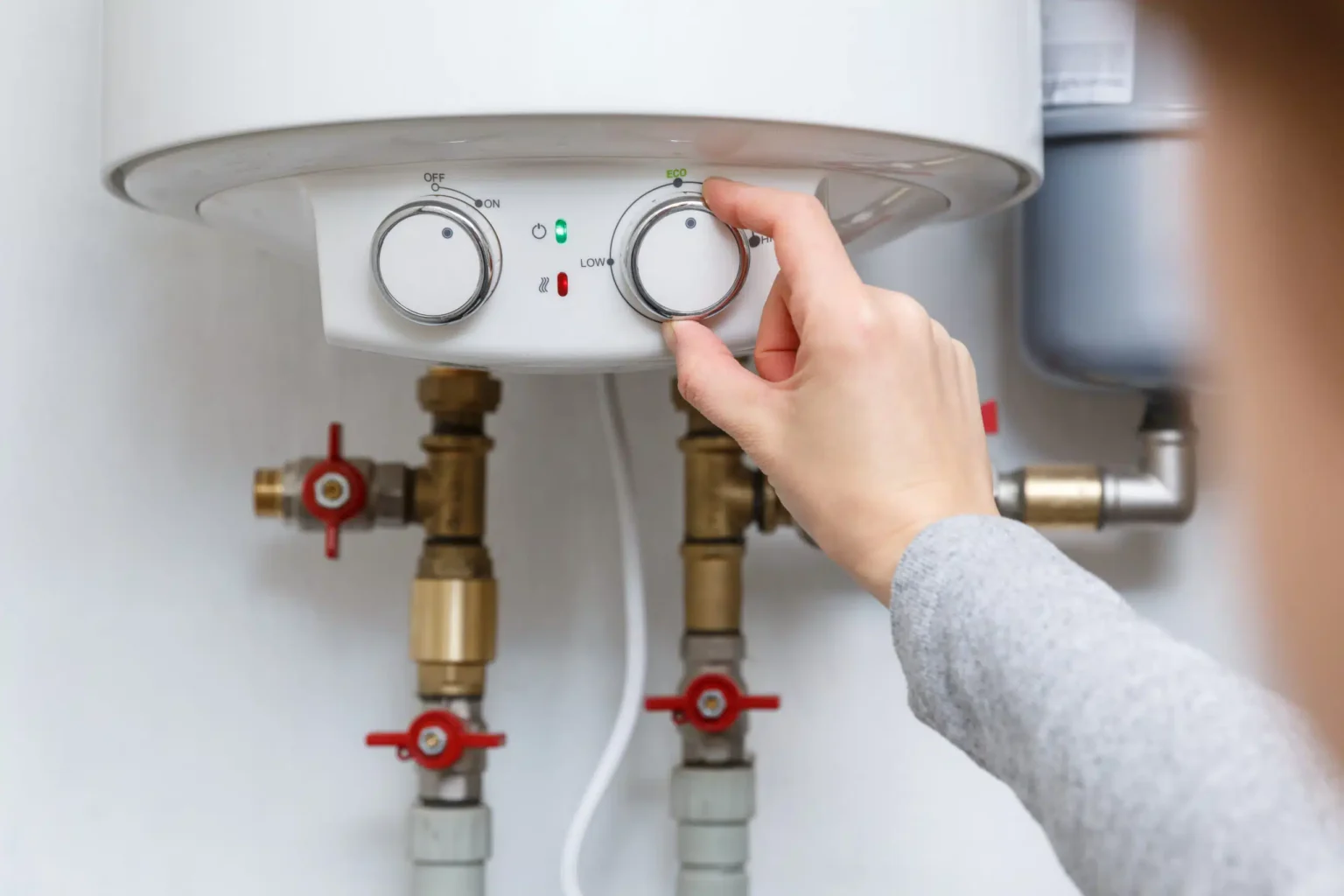 Homeowner adjusting the temperature controls on a water heater in Peachtree City